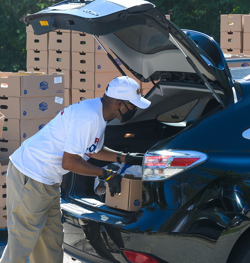 Photo of man loading car with food while wearing mask.