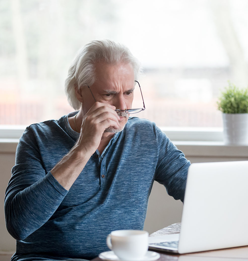 Photo of man looking quizzically at his computer screen