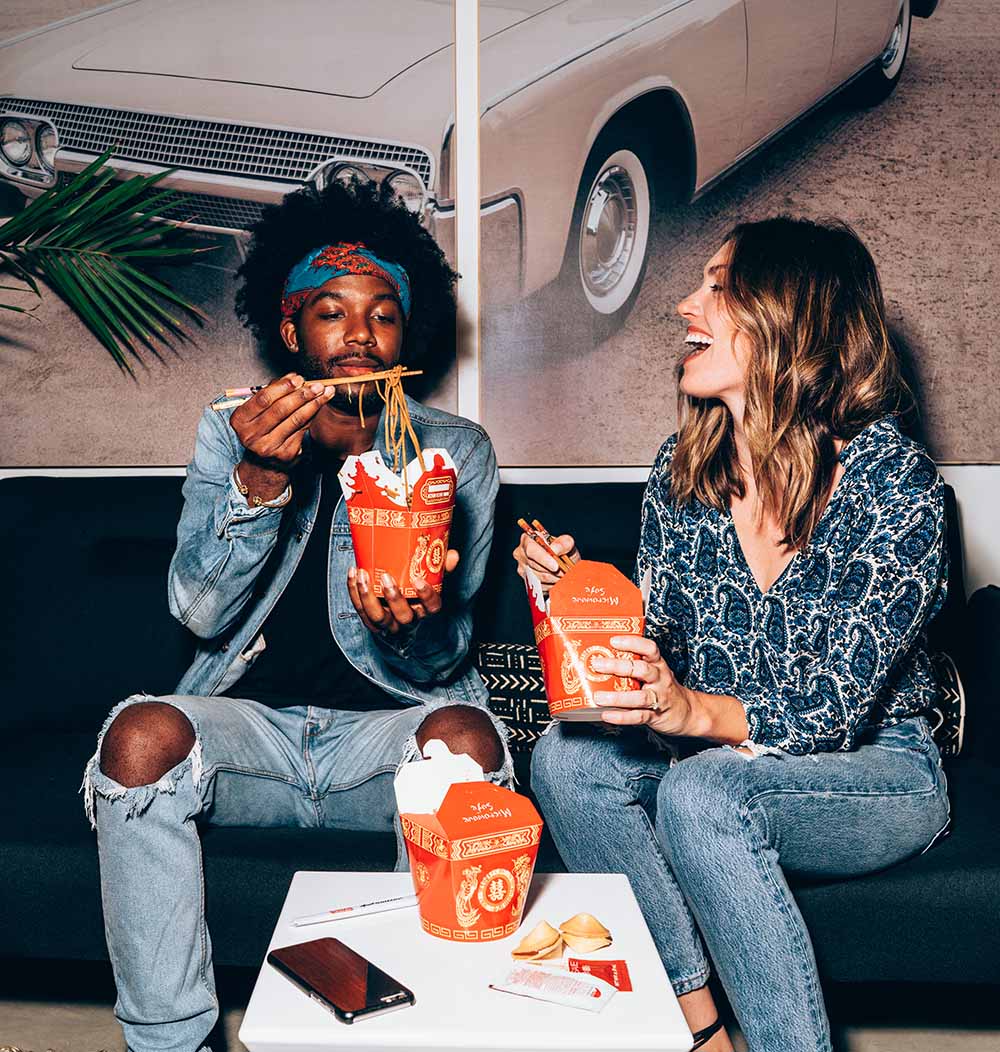 A photo of a couple eating noodles.