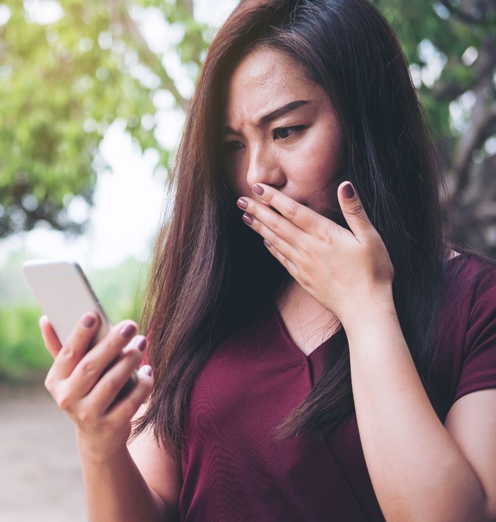 An image of a woman shocked because she has been the victim of an ID spoofing scam.
