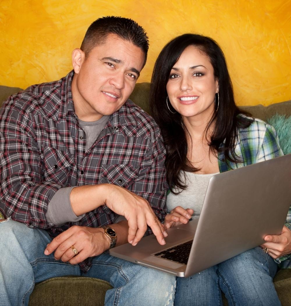 An image of a couple on the couch with a computer.