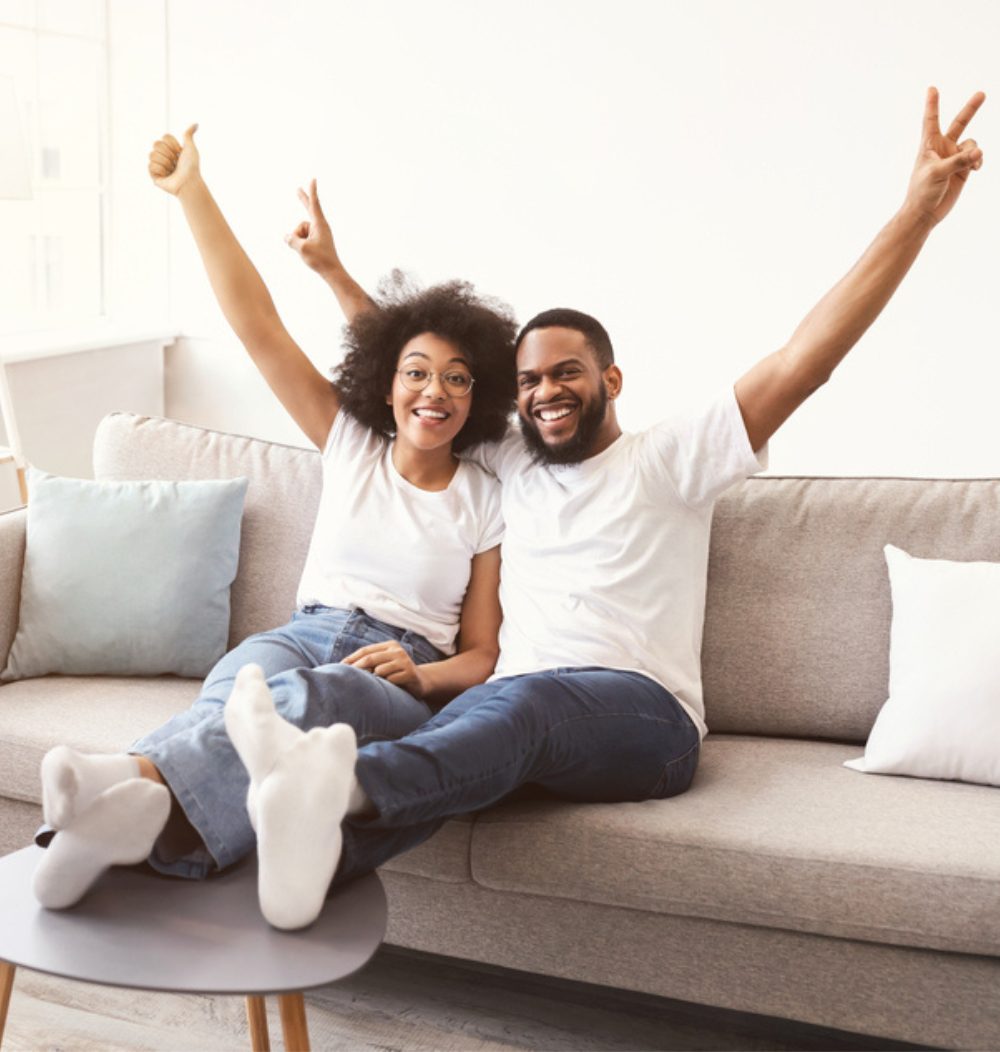 An image of a couple on couch in new home looking happy.